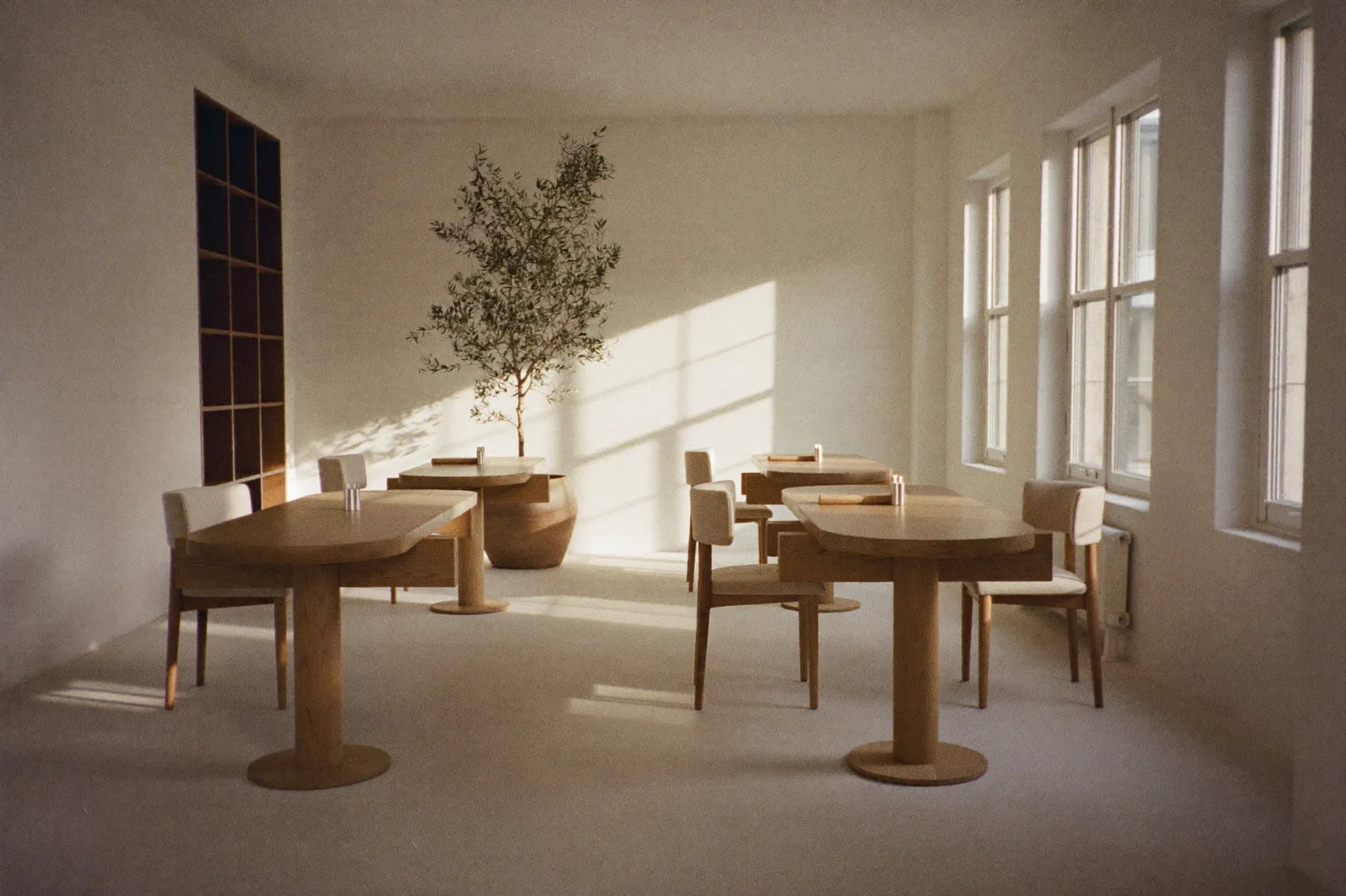The atelier interior: pale floor, oak tables, tall arched windows